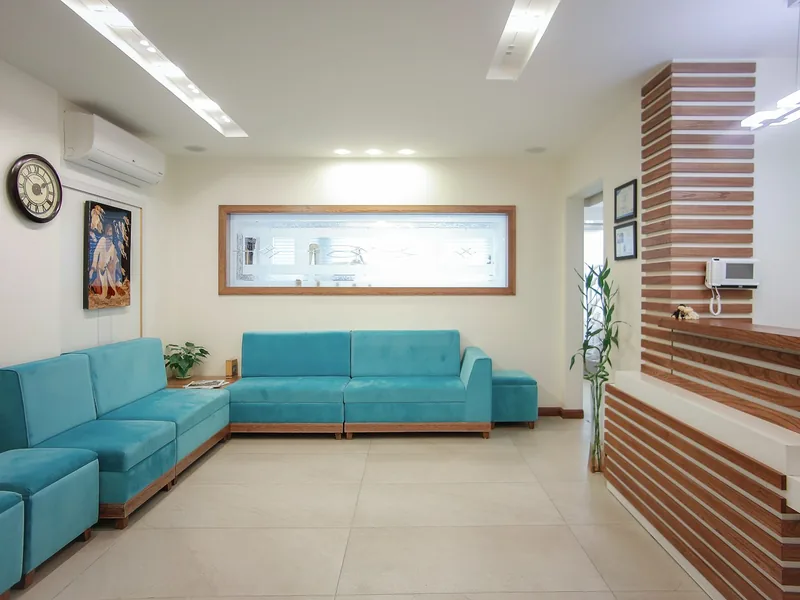 Sala de espera con sillones turquesa, reloj de pared y luz natural