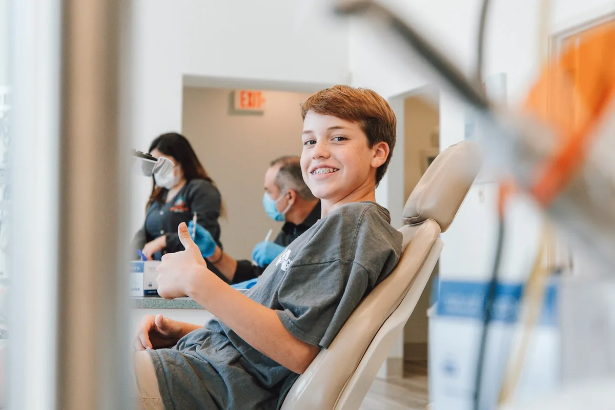 Chico sentado en el sillón odontológico, sonriendo durante un control de rutina