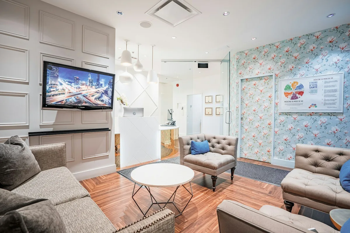 Sala de espera de la clínica con sillones tapizados y pantalla informativa
